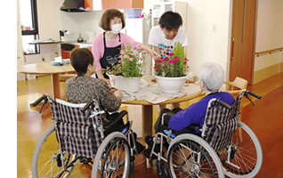 入居者と職員が一緒に花の活動をしている風景。車いすの利用者も参加している。